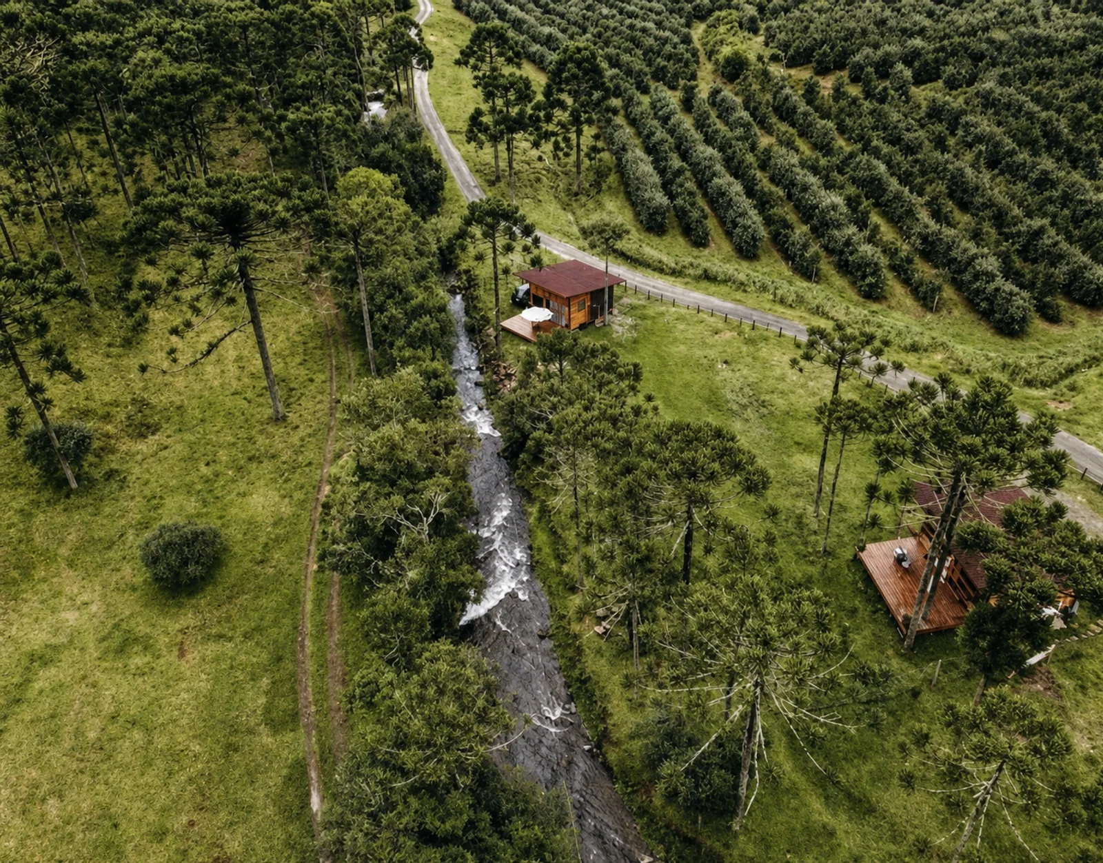 Vista aérea das cabanas, do riacho e da paisagem rural